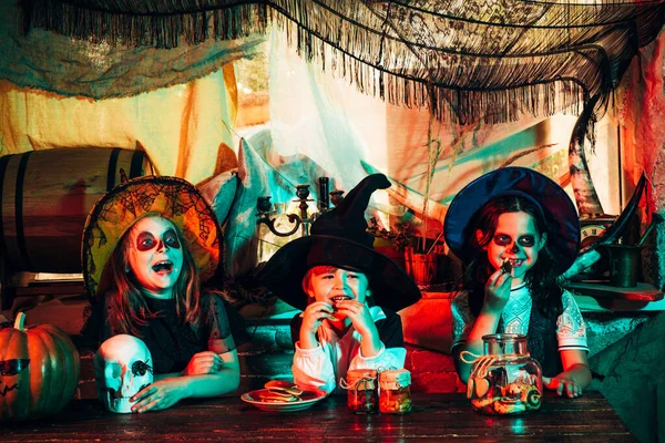 Gruppenkinder wie Zombie oder Hexe bereit für Tricks oder Leckereien. Kinderfreunde tragen ein altes Holzhaus im Halloween-Kostüm mit Kürbis. Calaverita. — Stockfoto