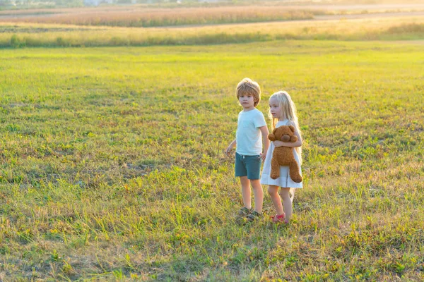 Niños felices niña y niño corriendo en el prado en verano en la naturaleza. Vida en el campo. Niños felices agricultores divirtiéndose en campo de primavera . — Foto de Stock