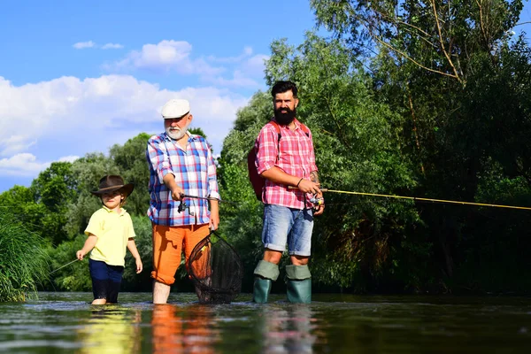 Ragazzino su un lago con suo padre e suo nonno. Buon pescatore con canna da pesca. 3 uomini che pescano sul fiume in estate. Buon fine settimana concetto . — Foto Stock