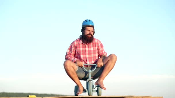 Бородатый мужчина, улыбающийся и веселящийся на велосипеде. Забавный человек с детским велосипедом на проселочной дороге. Человеческие эмоции и образ жизни . — стоковое видео