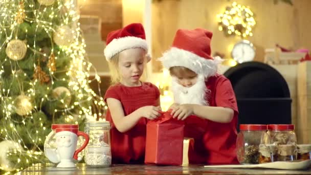 Crianças de Natal - filha e filho ou irmã e irmão abrindo presente de Natal. Miúdos giros a celebrar o Natal. Um presente de presente para as crianças do Pai Natal. Criança feliz se divertindo com presente . — Vídeo de Stock