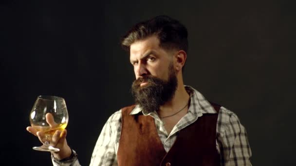 Homme ou homme d'affaires boit du cognac sur fond noir. L'homme barbu joyeux boit du cognac cher. Vieille boisson au whisky traditionnelle - boisson messieurs . — Video