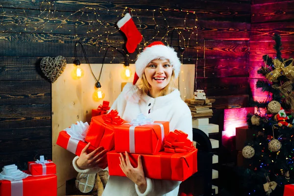 Jeune femme avec des boîtes cadeaux de Noël devant l'arbre de Noël. Joyeux jeune femme portant un costume de Noël sur un mur en bois. Portrait d'une jeune femme souriante . — Photo