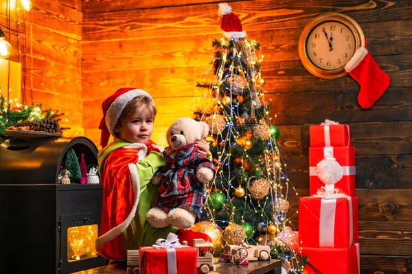 Lindo niño pequeño jugar cerca del árbol de Navidad. Regalos y sorpresas. Feliz Navidad y feliz año nuevo. Los niños disfrutan de las vacaciones de invierno en casa. Hogar lleno de alegría y amor. Día de la familia Navidad — Foto de Stock