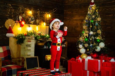 Neşeli yüzlü, Noel ağacı süsleyen ve eğlenen bir çocuk. Yeni yıl sürprizi hediyeleri. İyi tatiller. Güzel bebek Noel 'in tadını çıkar. Tatil indirimleri.