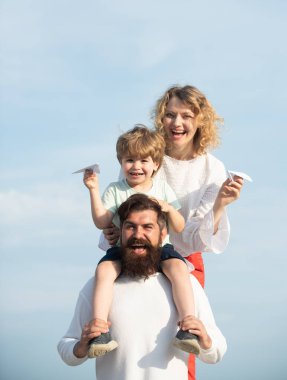 Çocuk bakımı. Mutlu bir aile. Anne ve baba, yaz aylarında doğada oyuncak kağıt uçakla çayırda. Ebeveynlik. Aile, yaz tatillerini sever..