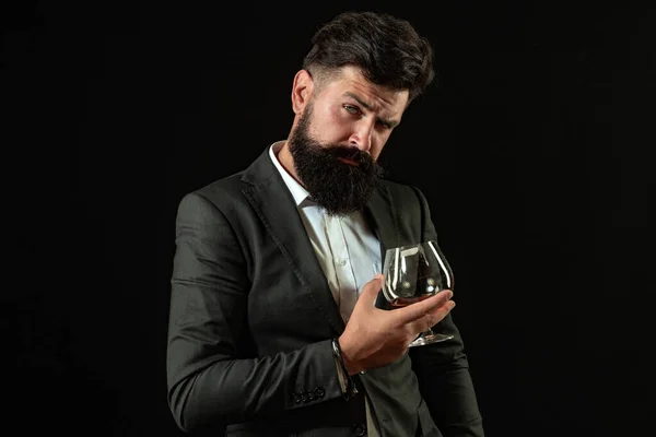 Przystojny brodaty biznesmen pije drogą whisky. Sommelier człowiek. Człowiek z brodą trzyma szklankę brandy. — Zdjęcie stockowe