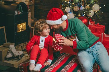 Kış Noel heyecanı. Hediye duyguları. Kış kıyafetleri içinde babası olan mutlu bir çocuk Noel ağacının yanında Noel Baba 'yı düşün..