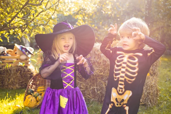 Een snoepje of ik schiet. Kinderen glimlachen op een Halloween feest. Happy Halloween Schattige kinderen dochter en zoon het maken van grappige gezichten met een pompoen. — Stockfoto