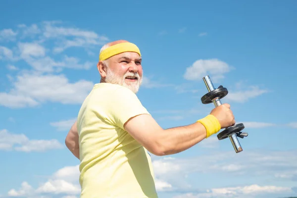 Vecchio uomo maturo che si esercita con i manubri. Sportivo senior nel centro sportivo. Centro benessere o centro di riabilitazione per anziani anziani pensionati. Uomo anziano sportivo che solleva manubri nel centro sportivo. — Foto Stock