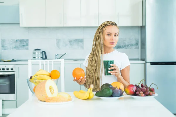 Sonriente mujer sana bebe batido verde en la cocina. Haciendo menú de batidos. Espirulina fresca. Complementos alimenticios. Concepto vegano. Bienestar y concepto de pérdida de peso. Superfood . — Foto de Stock