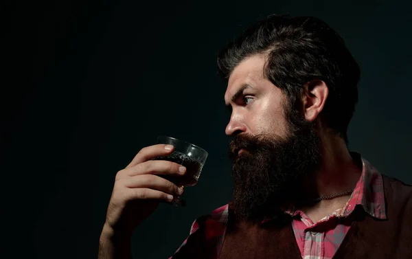Retro vintage man with whiskey or scotch. Fashionable man in white shirt and suspenders. Bearded and glass of whiskey.