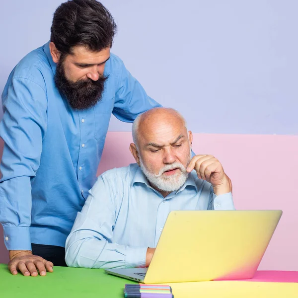 两个英俊的商人坐在桌子旁边，办公室里装着笔记本电脑。 自由工作方式和商务会议. — 图库照片