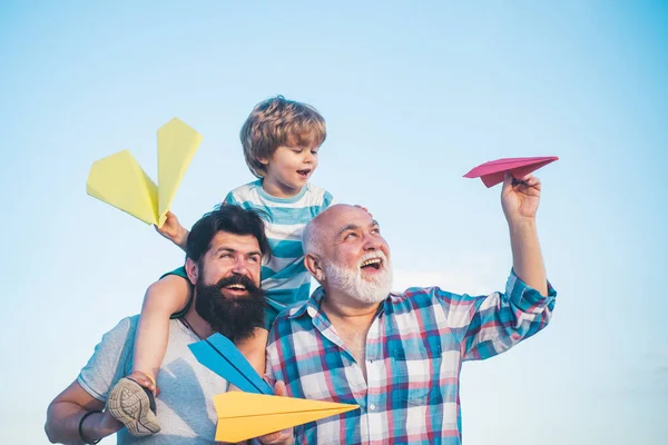 Junge mit Vater und Großvater genießen zusammen im Park vor blauem Himmel Hintergrund. Großvater spielt. glücklich drei Generationen von Männern haben Spaß und lächeln auf blauem Himmel Hintergrund. — Stockfoto