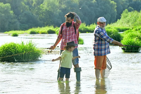 老少皆宜 父亲、儿子和祖父在一起放松。 在河里钓鱼 年轻人-成年人的概念. 有钓竿的渔夫很开心. — 图库照片