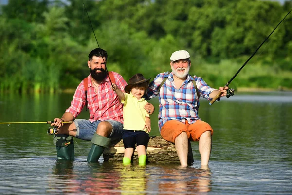 Family fishermen fishing with spinning reel. Summer weekend. Happy grandfather, father and grandson with fishing rods on river berth. Happy weekend concept. — Stock Photo, Image