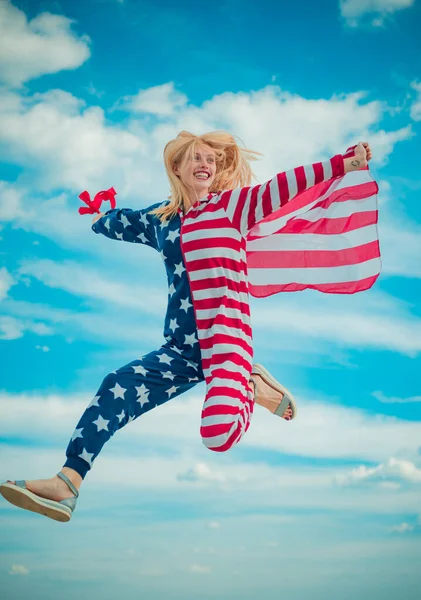 快乐的女人举着美利坚合众国的国旗，无忧无虑地跳着，张开双臂，蓝蓝的天空。美国独立日，7月4日. — 图库照片