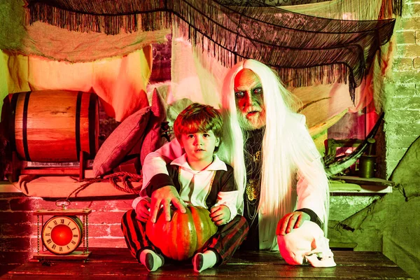 Son and father with carve pumpkins for Halloween. Portrait of funny family during Halloween. Grandpa and grandson with pumpkin together as preparation for Halloween. — ストック写真