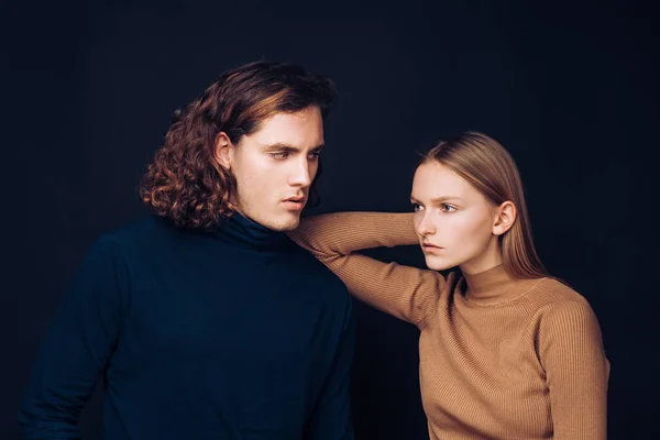 Closeup portrait of fragile blonde and young man. Relationship between male and female. Picture of two friends are standing together over a dark wall. Best friends are ready to overcome everything to — 图库照片