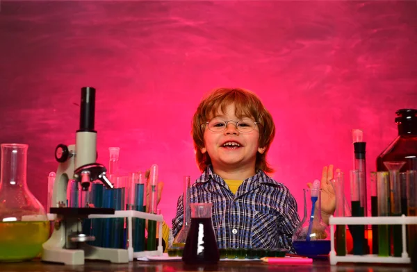 Alegre niño sonriente divirtiéndose contra la pared azul. Clases de química escolar. Preescolar. Lo que se enseña en química —  Fotos de Stock