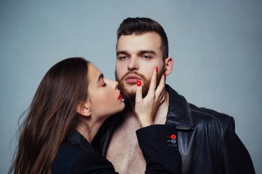 Girlfriend passionate red lips and man leather jacket. She adores male brutal beard. Passionate hug. Couple passionate people in love. Man brutal well groomed macho and attractive girl cuddling clipart