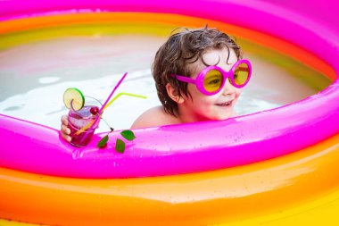 Mutlu çocuk güneşli bir günde yüzme havuzunda eğleniyor. İbiza 'daki plaj kulüpleri. Sıcak bir yaz gününde havuzda oynayan küçük mutlu çocuk..