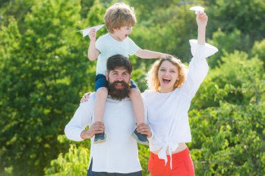 Mutlu aile ve küçük oğlu mavi gökyüzünde oynuyorlar. Baba, anne ve oğul parkta. Mutlu aile gülümsemesi ve kucaklaşması. Baba, anne ve bebek dışarıda birlikte oynuyorlar..