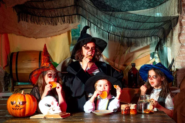 Dia das Bruxas engraçado. Miúdos engraçados em trajes de carnaval dentro de casa. Grupo de bruxinha com uma abóbora e doces. Halloween crianças festa . — Fotografia de Stock