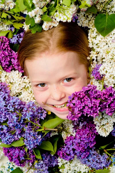 Lachend klein meisje, een portret van mooi lente meisje in bloeiende tuinen, jong charmant elegant lente model, outdoor mode foto van mooie jonge kleuterschool omgeven door bloemen. — Stockfoto