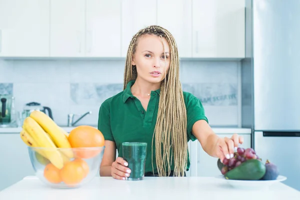 Vegetarian diet trend. Smiling young woman drinking green smoothie in kitchen. Green juice. Vegan meal diet at home. Fitness diet nutrition. Natural antioxidant. Weight loss.