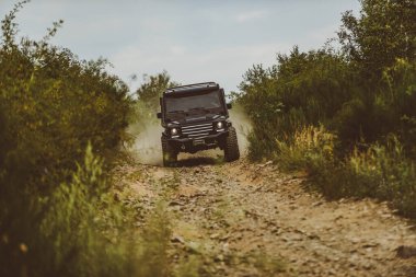 Tekerlekleri ve kumdaki toza dönüşen off-road 'u hareket ettir. Dağ yolunda off-road yolculuğu. Gezgin off-road aracı. Çamurlu bir arazide izler. Yol macerası. Macera seyahati.