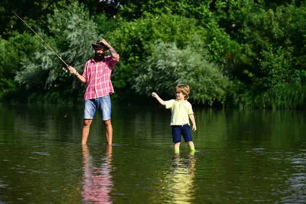 Father and son fishing. Father with his son on the river enjoying fishing holding fishing rods.