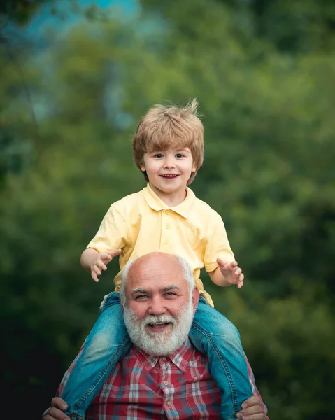 Abuelo hablando con su nieto. Abuelo barbudo y nieto jugando con el día soleado. Niño feliz jugando con alas de juguete brazos contra el fondo del cielo de verano . —  Fotos de Stock