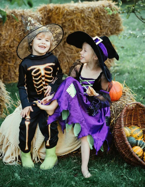Csokit vagy csalunk. Halloween jelenet aranyos gyerekekkel. Boldog gyerekek csontvázzal és boszorkányjelmezzel, akik cukorkát tartanak és esznek. Halloween édességek. — Stock Fotó