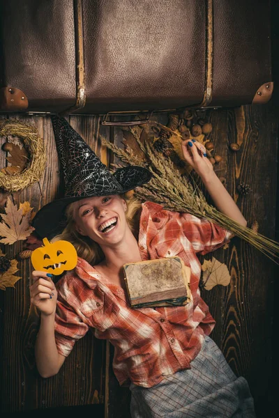 Belle jeune femme surprise en chapeau de sorcières et costume tenant citrouille. Jolie fille modèle en costume d'Halloween. Sorcière d'Halloween avec citrouille. Drôle d'expression. Des gens heureux. S'amuser . — Photo