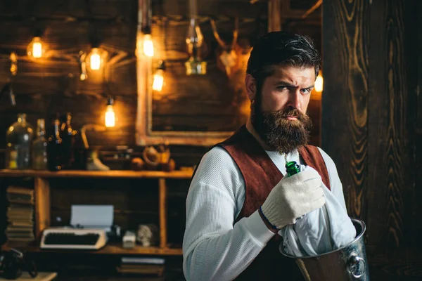 Serious barman. Restaurant staff. Bearded hipster wear waistcoat. Pub retro vintage interior. Barman with beard. Hipster barman concept. bearded waiter or servant. Vintage pub. Swag guy with alcohol.