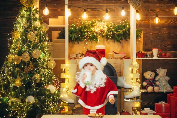 Der Weihnachtsmann isst an Heiligabend Plätzchen und trinkt Milch. Kinder Weihnachtsmann genießen in serviert Lebkuchen und Milch. Weihnachten für Kinder. — Stockfoto