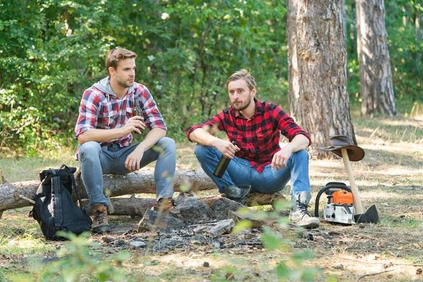 캠프 어드벤처와 여행 컨셉. 관광객들의 휴식. 일단 의 친구들 이 숲 속에서 소풍을 즐기고 맥주를 마십니다. 친구 두 명 이 숲 속에 앉아 맥주를 마시고 있는 모습. — 스톡 사진