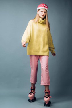 Stüdyoda poz veren genç sarışın kadın gri arka planda pembe patenler giyiyor. Süper eğlenceli aktif dinlenme, hafta sonu, yetişkinler için tatil kavramı.