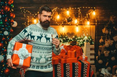 Noel süsleri. Sakallı, modern Noel Baba örgü süveter giymiş. Noel Baba şapkalı adam. Noel Baba evde..