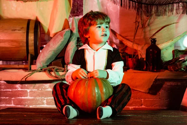Ragazzo divertente in costume da carnevale in casa. I bambini in America festeggiano Halloween. Decorazioni di Halloween. Bambino allegro con zucche e caramelle . — Foto Stock