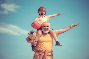 Sporcu büyükbaba ve mavi gökyüzü arka planında basketbol topu olan sağlıklı çocuk. Küçük çocuklar için spor. Farklı nesiller.