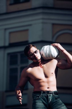 Ölüm - genç adam. Büyük zombi adam cadılar bayramı vampiri mi yoksa kanlı, yaralı bir savaş askeri mi ve balkabaklı kırmızı kan mı? Kaslı vücudu ve balkabağı olan genç bir adam. Spor ve sağlıklı yiyecekler, Cadılar Bayramı kabağı