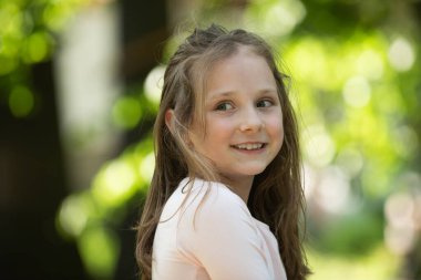 Çocuk güneşli bir günde yürüyor. Park doğasında duygusal bir çocuk. Parktaki genç kız. Güzel bir genç kızın mutlu bir hayat tarzı portresi, tatlı bir gülümsemesi var..