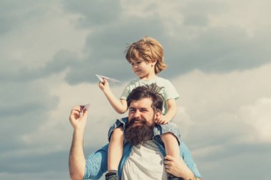 Babalar günün kutlu olsun. Baba ve oğul arka planda oynuyorlar. Baba ve oğul parkta. Hayal Özgürlüğü - Neşeli Çocuk Kağıt Uçakla Oynuyor.