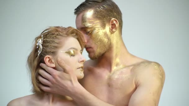 Pareja tocándose entre sí con maquillaje dorado aislado sobre un fondo blanco. Juegos eróticos de pareja enamorada. Sexy pareja con maquillaje de arte corporal dorado. Relaciones hombre-mujer. Máscara de colágeno dorado . — Vídeos de Stock