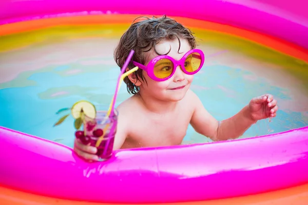A fiú boldogan úszik a medencében. A gyerekek szórakoztatóak. A gyerekek boldogok. Gyermek medence. Nyaralás és utazás. Nyaralás és nyaralás koncepciója. — Stock Fotó