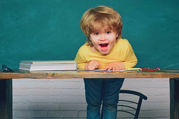 L'éducation. Joyeux enfant souriant au tableau noir. Examen dur. Un écolier. Heureux élèves souriants dessinant au bureau . — Photo