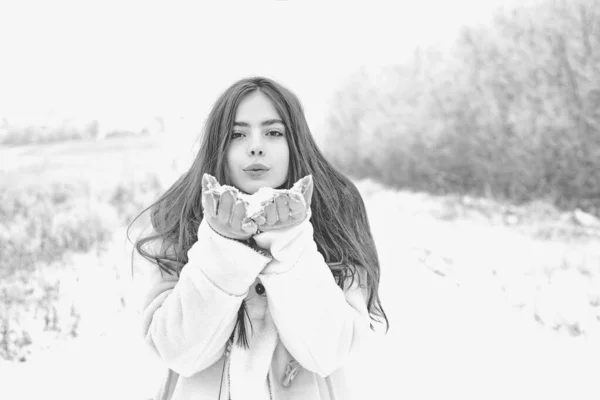 Adoro o inverno. Menina legal feliz soprando lábios vermelhos faz beijo de ar vestindo uma camisola branca sobre fundo nevado. Meninas encantadoras em férias de inverno. Mulher de inverno soprando lábios rosa envia beijo de ar . — Fotografia de Stock