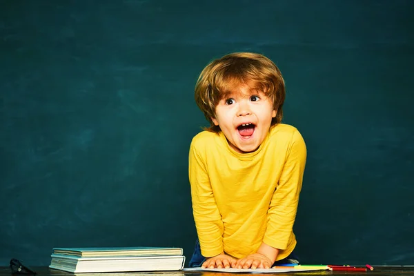 Kid is learning in class on background of blackboard. Happy school kids. Talented child. School and education concept. Stock Image
